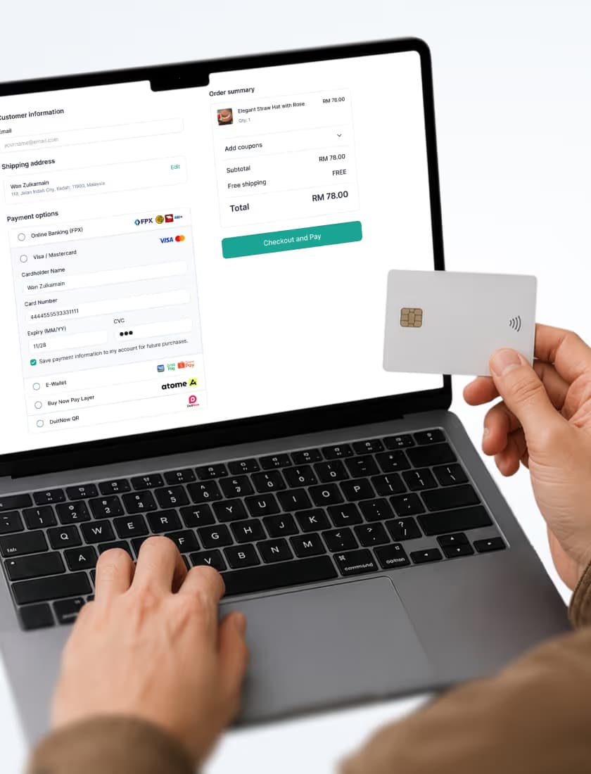 Person holding contactless card while typing on laptop displaying online payment checkout screen.