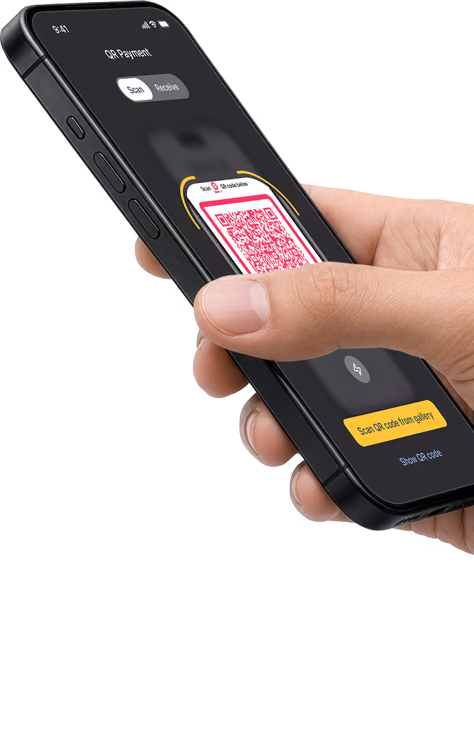 A hand holding a phone with bank app QR scanner open ready to scan merchant phone with DuitNow QR code